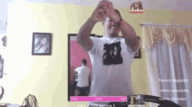 a man is dancing in a living room while wearing a white shirt .