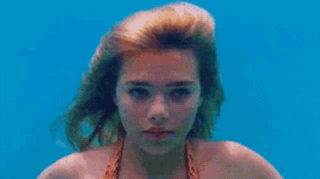 a woman in a bikini is swimming underwater in a pool