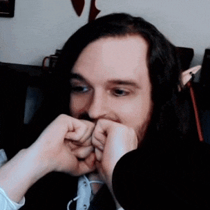 a man with long hair and a beard is making a funny face with his hands .