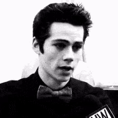 a black and white photo of a man wearing a bow tie and a microphone .