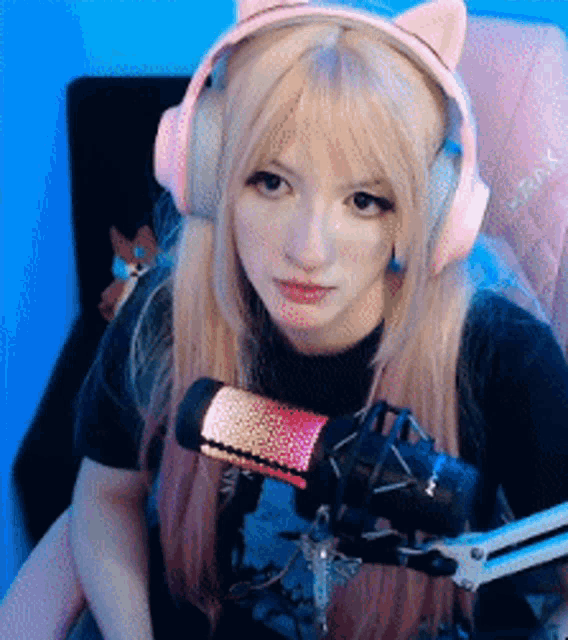 a girl wearing pink headphones and a microphone looks at the camera