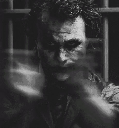 a black and white photo of the joker holding a gun .