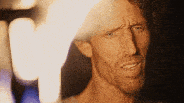 a man with a beard is making a funny face in front of a fire