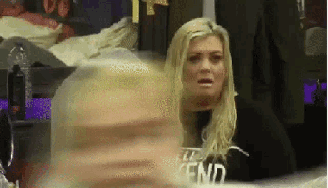 a woman with blonde hair is sitting in front of a sign that says " the end "