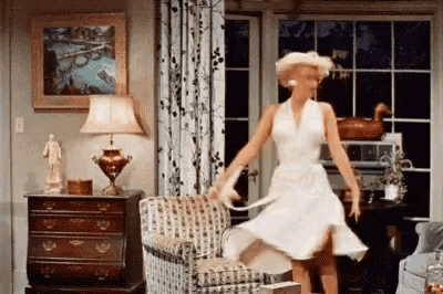 a woman in a white dress dancing in a living room