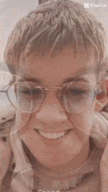 a boy wearing glasses and a white shirt is smiling in a photo taken by the faceapp app