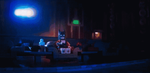 a lego batman is sitting in a dark theater