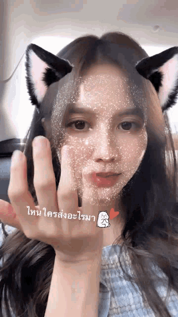a girl with cat ears on her face is making a stop sign