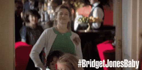 a woman in a green shirt and white cardigan is standing in a restaurant .