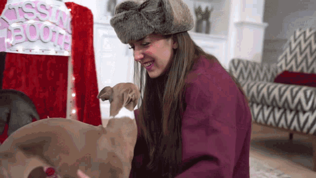 a woman petting a dog in front of a kissing booth sign