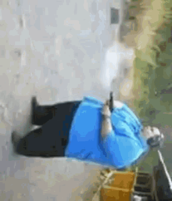 a man in a blue shirt is holding a gun in his right hand
