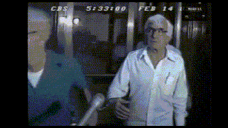 a man in a white shirt is standing in front of a microphone with cbs at the top of the screen