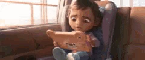 a baby doll is sitting in a car seat holding a teddy bear .
