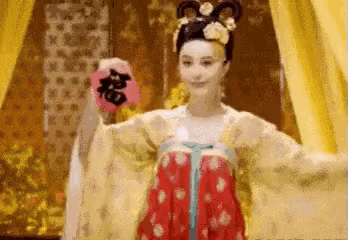 a woman in a traditional costume is holding a fan in her hands .