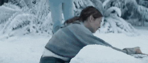 a woman is laying on the ground in the snow making a snowman .
