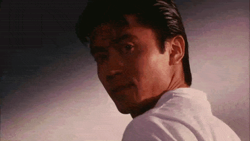 a man in a white shirt is looking over his shoulder at something .
