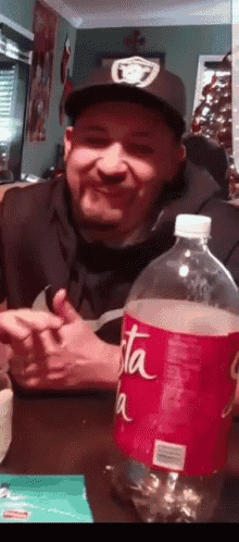 a man sitting at a table with a bottle of coca cola