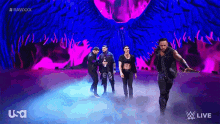 a group of wrestlers are walking on a stage with a purple background and usa live written on it
