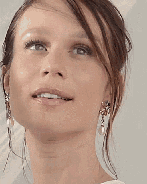 a close up of a woman wearing earrings and looking up