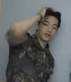a man in a military uniform is holding his hand to his head .