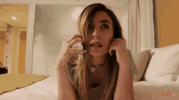 a woman is laying on a bed talking on her phone