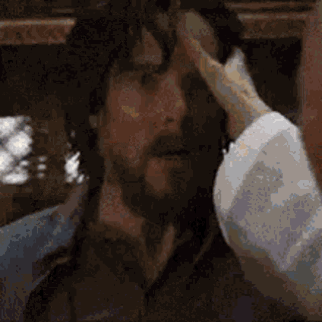a man with a beard is rubbing his forehead with his hand