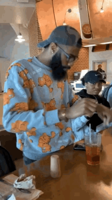 a man wearing a garfield sweatshirt is sitting at a table