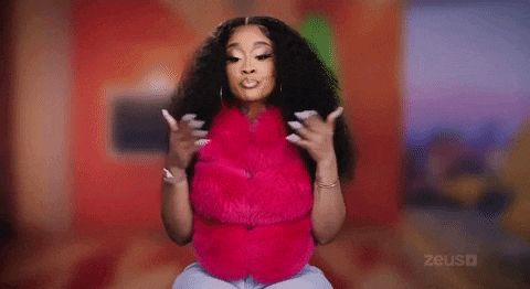 a woman wearing a pink fur vest and earrings is holding her hair .