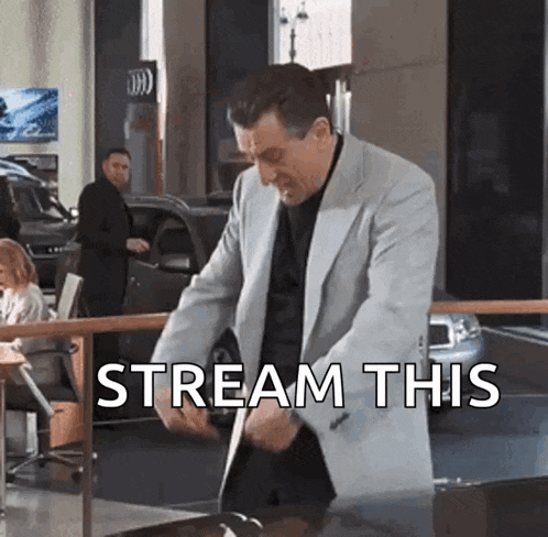 a man in a suit is standing in front of a car with the words stream this written above him