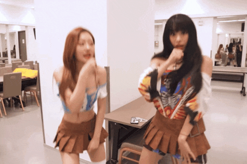 two women are dancing in a room with a table and chairs in the background