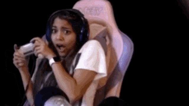 a woman is sitting in a pink gaming chair holding a video game controller .