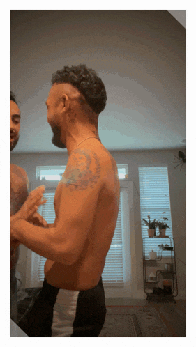 a man without a shirt is looking at himself in the mirror