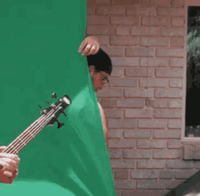 a man is playing a bass guitar in front of a green screen