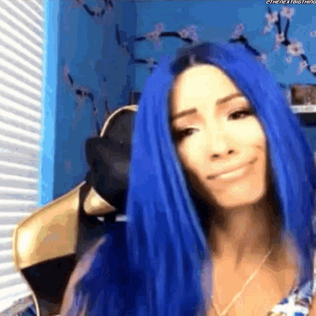 a woman with blue hair is smiling in front of a window .