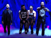 a man in a black shirt that says " i 'm your man " is standing next to two other men