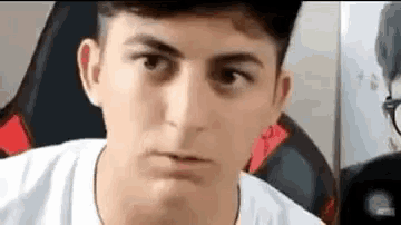 a close up of a young man making a funny face while sitting in a chair .