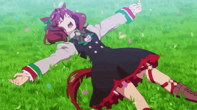 a girl in a black and red dress is laying in the grass with her arms outstretched