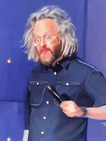 a man with glasses and a beard holds a microphone in his hand