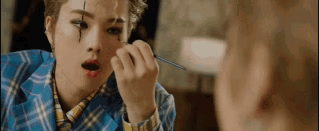 a woman is applying makeup to her face and looking at herself in the mirror .