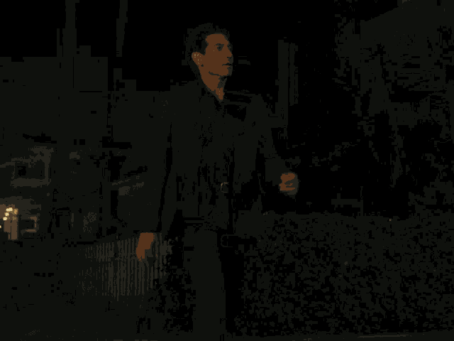a man in a suit and black shirt stands in the dark