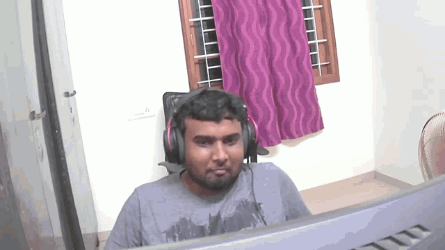 a man wearing headphones sits in front of a msi computer