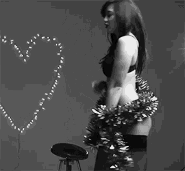 a black and white photo of a woman in lingerie holding a tinsel