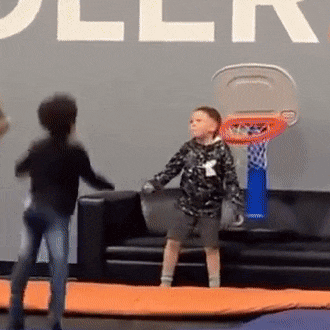 two young boys playing basketball in front of a wall that says roller