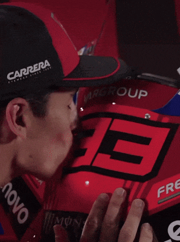 a man wearing a red ducati hat is smiling and giving a thumbs up