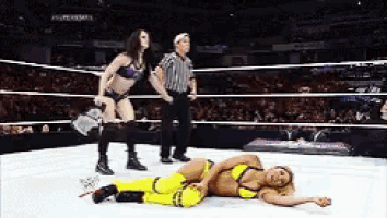 a woman is laying on the ground in a wrestling ring