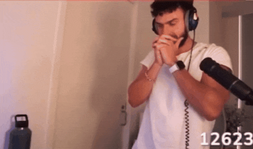 a man wearing headphones and a watch stands in front of a microphone with the number 12623 on the bottom right