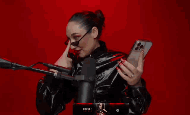 a woman holding a cell phone in front of a microphone with the word obstacle on the bottom