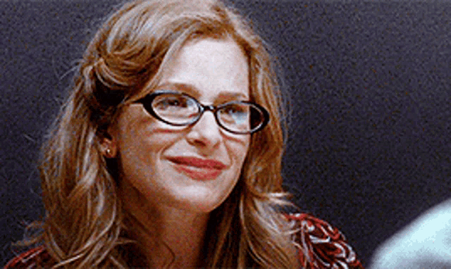 a close up of a woman wearing glasses and smiling