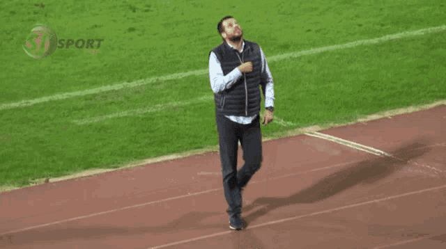 a man is walking on a track with the word sport on the bottom