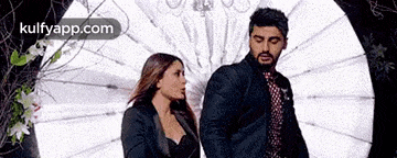 a man and a woman are standing next to each other in a room .